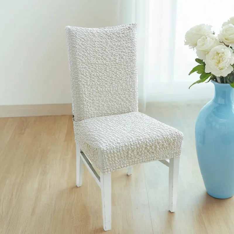 Close-up of white dining chair slipcover showing soft, fluffy Plume Bubble fabric texture and seamless fit.